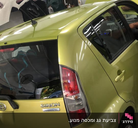 מכונית ירוקה במוסך עם חלקי רכב נוספים